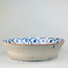 Wide view of the entire lebrillo laid flat on a neutral surface, emphasizing the radial symmetry and bold contrast of cobalt blue on white tin glaze, perfect for rustic or Mediterranean wall art or table styling.