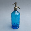 Vintage French blue glass soda siphon with pewter spout, shown in full view on a grey background, reflecting elegant Art Deco design from the 1920s–1940s.