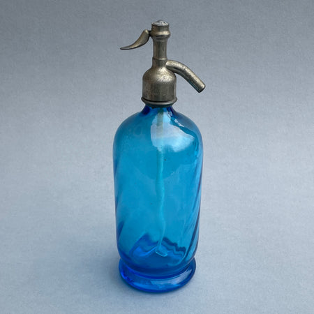 Vintage French blue glass soda siphon with pewter spout, shown in full view on a grey background, reflecting elegant Art Deco design from the 1920s–1940s.