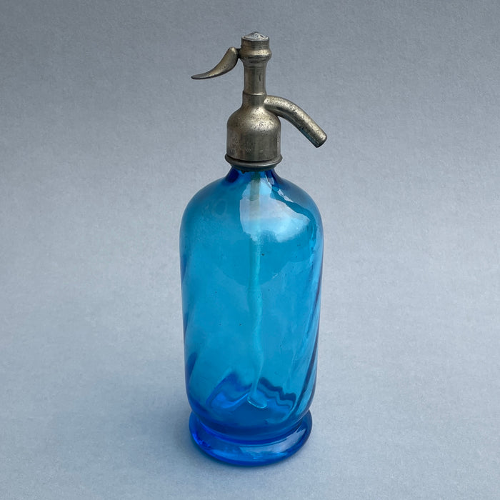 Vintage French blue glass soda siphon with pewter spout, shown in full view on a grey background, reflecting elegant Art Deco design from the 1920s–1940s.