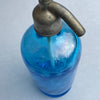 Highlight on mouth-blown glass body with swirling internal tube, emphasizing craftsmanship and antique soda bottle technology.
