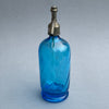Close-up of antique blue glass soda bottle body with curved form and rich cobalt tones, highlighting air bubbles and natural imperfections in the glass.
