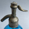 Detail of patinated pewter siphon top stamped "NOVELTY LITRE GARANTI," showcasing vintage French engineering with rustic charm.
