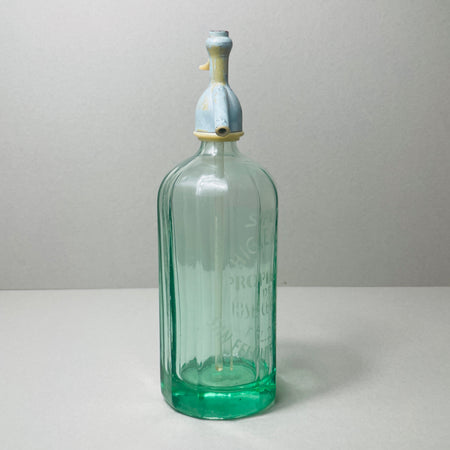 Rear angle of mid-century Spanish siphon bottle in green glass, showing clean fluted body lines and full silhouette of the antique metal siphon top with white lever detail.