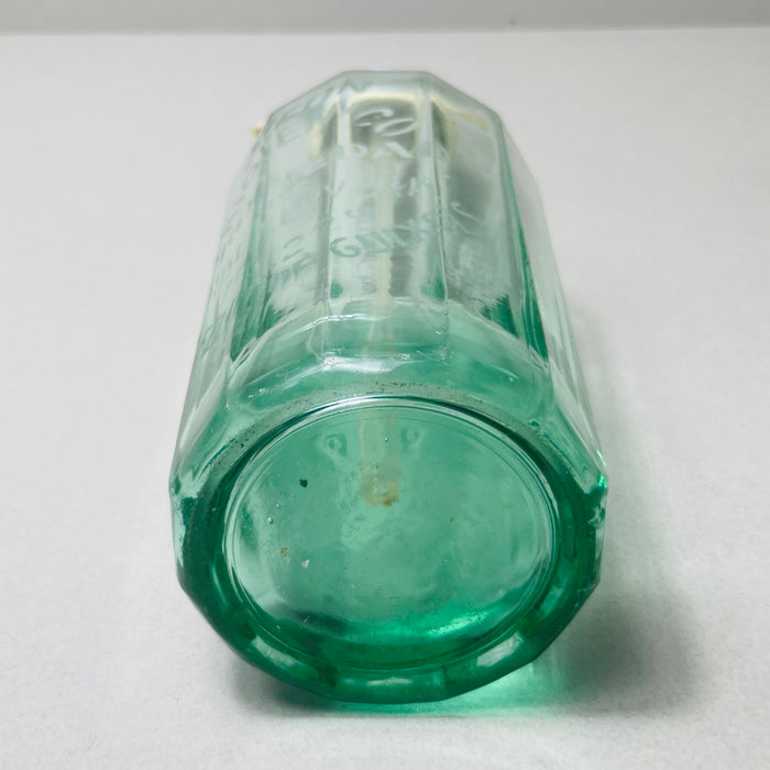 Light-filled image showcasing the clarity and thickness of vintage green soda glass. Minimalist background accentuates the bottle’s classic soda siphon shape and retro details like the ivory siphon lever and painted metal top.