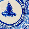 Central decoration on a 19th-century Spanish Manises plate, hand painted in deep cobalt blue over opaque white tin glaze. The symmetrical foliate motif resembles a stylized palmette or flower rising above scrolling leaves and small rosettes, forming the focal point of this antique majolica charger and Mediterranean ceramic wall art.