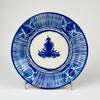 Antique Manises pottery plate from Spain with cobalt blue brushwork on a creamy tin-glazed ground. The broad decorative charger features alternating bands of fine radial stripes and stylized botanical motifs around a central floral medallion, while age-related rim wear and glaze losses preserve the character of this 19th-century Spanish ceramic wall plate.