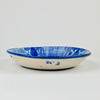 Large antique Spanish Manises plate in blue and white majolica, shown at human scale to convey its substantial decorative presence. The hand-painted cobalt design covers a deep earthenware charger with a central stylized flower, rhythmic striped border and traditional Valencian foliate ornament suited to a collected ceramic wall display.