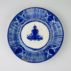 Antique Spanish majolica plate attributed to 19th-century Manises, Valencia, hand painted in cobalt blue over warm white tin-glazed earthenware. The deep circular charger combines a central foliate palmette with dotted borders, radiating striped panels and stylized fruit and floral motifs, creating distinctive ceramic wall art for Mediterranean decor.