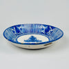 Antique Spanish ceramic charger attributed to Manises, with a deep rounded profile and hand-painted cobalt blue decoration across a warm cream tin-glazed surface. Alternating striped sections and stylized floral or fruit motifs frame the central palmette, while the repaired crack, rim fritting and glaze losses document extensive age and use.