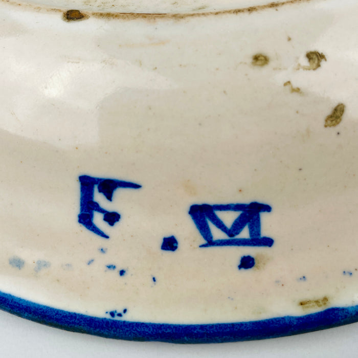 Antique Spanish majolica plate attributed to 19th-century Manises, Valencia, hand painted in cobalt blue over warm white tin-glazed earthenware. The deep circular charger combines a central foliate palmette with dotted borders, radiating striped panels and stylized fruit and floral motifs, creating distinctive ceramic wall art for Mediterranean decor.