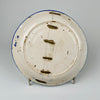Underside of the antique Spanish Manises majolica plate showing a long historic break secured with multiple metal staples across the foot ring and body. The old repair joins the tin-glazed earthenware sections and forms an important part of the charger’s history, while the white reverse also retains kiln marks, wear and scattered glaze losses.