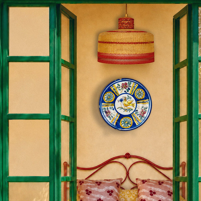 Antique Manises pottery charger with a stylized golden yellow bird at the center of a creamy white tin glazed surface. A dense radial border alternates cobalt blue fields, three pink floral panels and three green rosettes outlined in brown, making this Spanish ceramic plate striking wall art or a table centerpiece