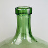 Close-up of the antique French demijohn's neck, showing the handblown glass lip and subtle asymmetry, with visible air bubbles and a thick olive-green rim—classic features of 1940s rural artisan craftsmanship. Macro image of demijohn neck and glass texture highlighting subtle air bubbles and slight asymmetry from traditional handblown technique.