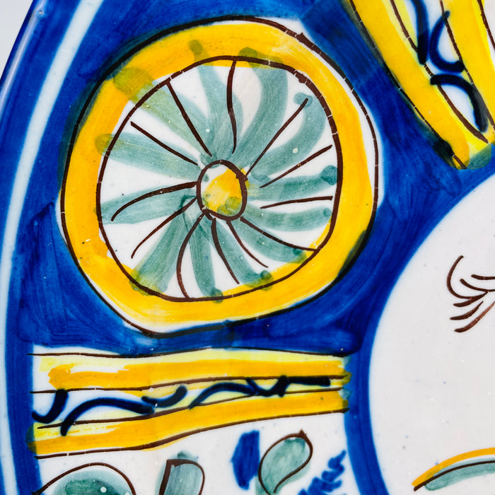 Antique large Manises bird charger in tin glazed earthenware, hand painted around circa 1900 with a golden yellow bird, cobalt blue radial border, pink flowers, green foliage and geometric rosettes. This Spanish majolica wall plate combines folk pottery character with the scale and color needed for a Mediterranean decor centerpiece.