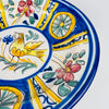 Rim condition on the large Manises bird plate showing several age related glaze losses and chips that reveal the warm buff earthenware beneath the cobalt edge. The plate remains visually complete, and the wear is clearly shown for collectors of antique Spanish pottery, majolica chargers and ceramic wall art.