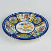 Central motif of the antique Manises wall plate, showing a stylized golden yellow bird with a long tail, fine brown feather lines, slim legs and a cobalt blue flower near its beak. Green leaves and sweeping stems complete the hand painted scene on white tin glazed earthenware from Valencia, Spain.