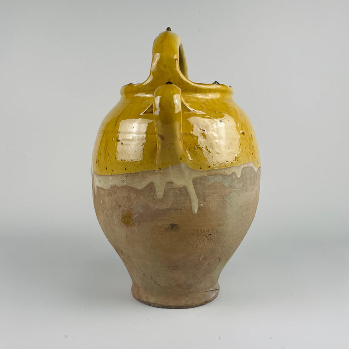 A close-up of the yellow glazed terracotta gargolette reveals subtle crackling, natural wear, and color variations that confirm its 19th century origin. This handcrafted cruche form is perfect for Mediterranean decor, cottage decor, and French country decor, bringing warmth and authenticity to any space through its rustic handmade character.