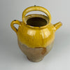 A detailed shot captures the mouth and spout of the antique yellow glazed French terracotta pot, showing glaze texture, edge wear, and natural variation. The craftsmanship and patina make it an appealing piece for farmhouse decor, rustic home decor, cottage decor, french country decor, and mediterranean decor. The pot’s earthen tones bring warmth and texture to any space featuring vintage French pottery.