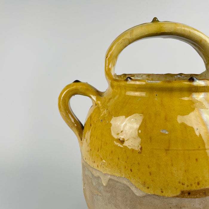 Detailed view of the handle of this antique French terracotta pot, showing the hand-applied glaze pooling and the rounded handle typical of rural vessels from Southern France. Ideal for farmhouse decor, rustic home decor, or Mediterranean decor, this piece brings old-world charm and authentic French craftsmanship into modern homes.