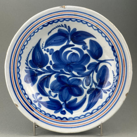 Spanish Talavera plate, hand-painted ceramic with cobalt blue floral design, shown from above to highlight the bold central motif and scalloped border.
