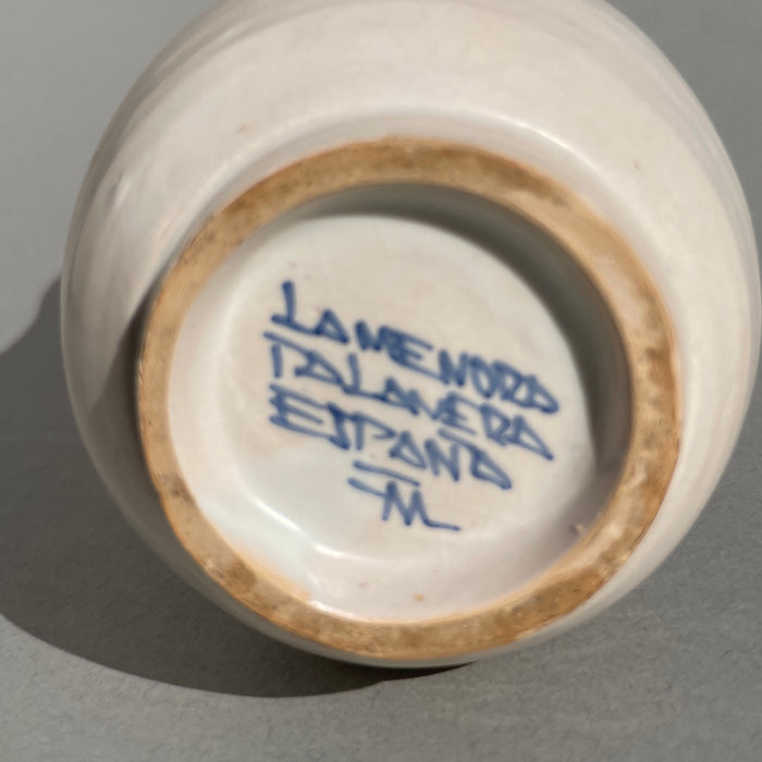 Ceramic apothecary jar from Talavera, featuring classic blue-and-white palette, ornate motif with religious and botanical symbolism, often found in 19th–20th century herbalist displays. Artisan-signed Talavera ceramic jar, underside stamp reading “La Menora Talavera España,” confirming its Spanish origin and hand-painted craftsmanship typical of the Talavera de la Reina region.
