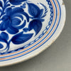 Spanish pottery wall plate, captured from a side angle to show shallow curvature and wide surface suitable for hanging.