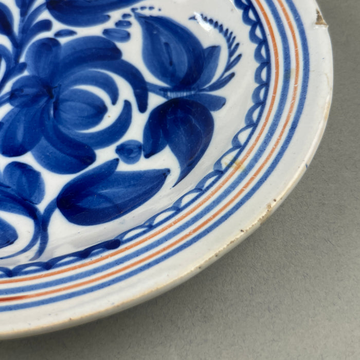 Spanish pottery wall plate, captured from a side angle to show shallow curvature and wide surface suitable for hanging.