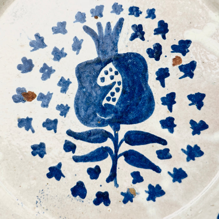Close-up of central pomegranate motif on glazed ceramic surface, capturing the bold Andalusian brushwork and aged texture of traditional Fajalauza pottery.
