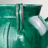 Side angle image of large French gargoulette in vibrant olive-green glaze, capturing the elegant curve of the handles and rare form typical of early 20th-century Southern French pottery.