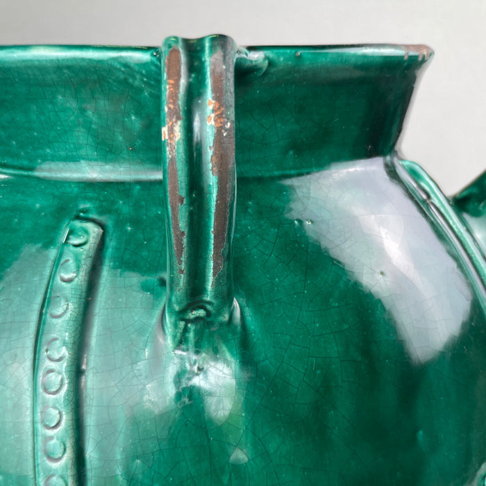 Side angle image of large French gargoulette in vibrant olive-green glaze, capturing the elegant curve of the handles and rare form typical of early 20th-century Southern French pottery.
