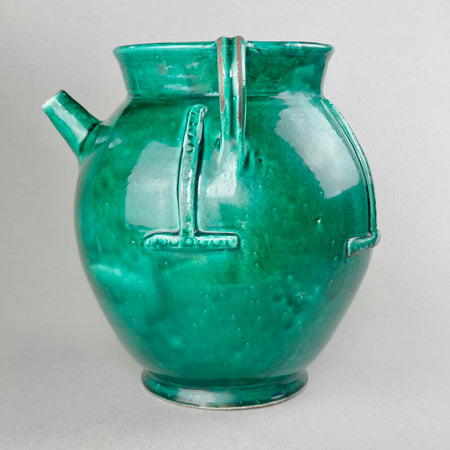 Rare vintage French green-glazed gargoulette with twin handles and relief bands, styled on rustic surface. Horizontal image of large French gargoulette showing off the rare proportions, rich green glaze, and softly aged patina, ideal for use as a centerpiece, statement vessel, or decorative art object.