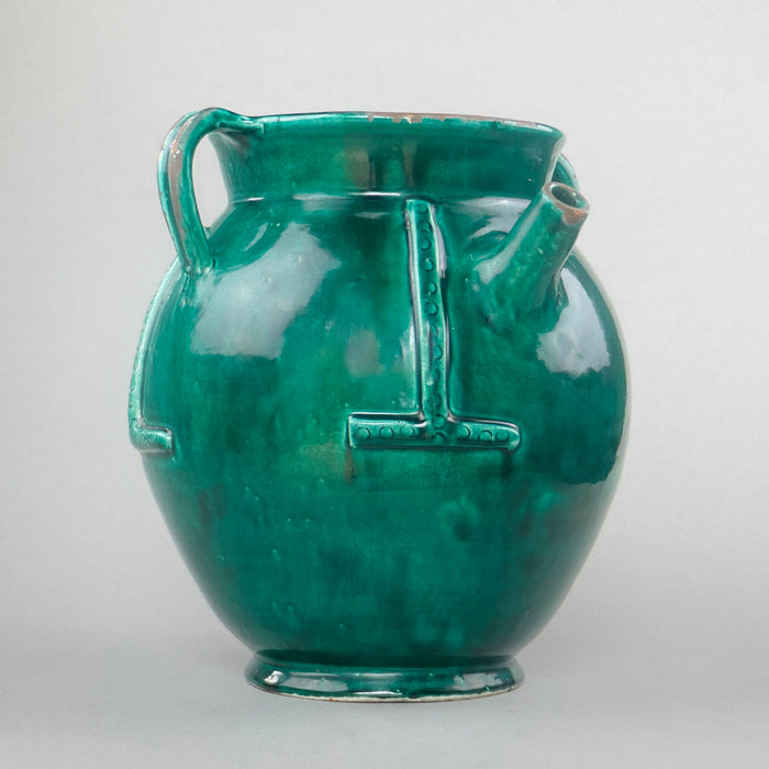 Rare vintage French gargoulette water jug with deep green glaze, twin handles, and a sculptural terracotta body, styled on a rustic surface with natural lighting to highlight its relief bands and handcrafted character.
