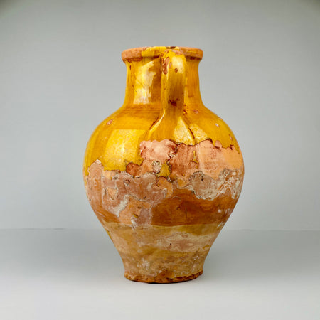 Vintage ceramic vase with yellow and brown glaze on a gray background.  Side profile of antique French gargolette water jug in terracotta with yellow glaze, showing curved spout and sturdy handle, ideal for styling in rustic farmhouse or Mediterranean interiors as an accent vase or sculptural decorative piece.