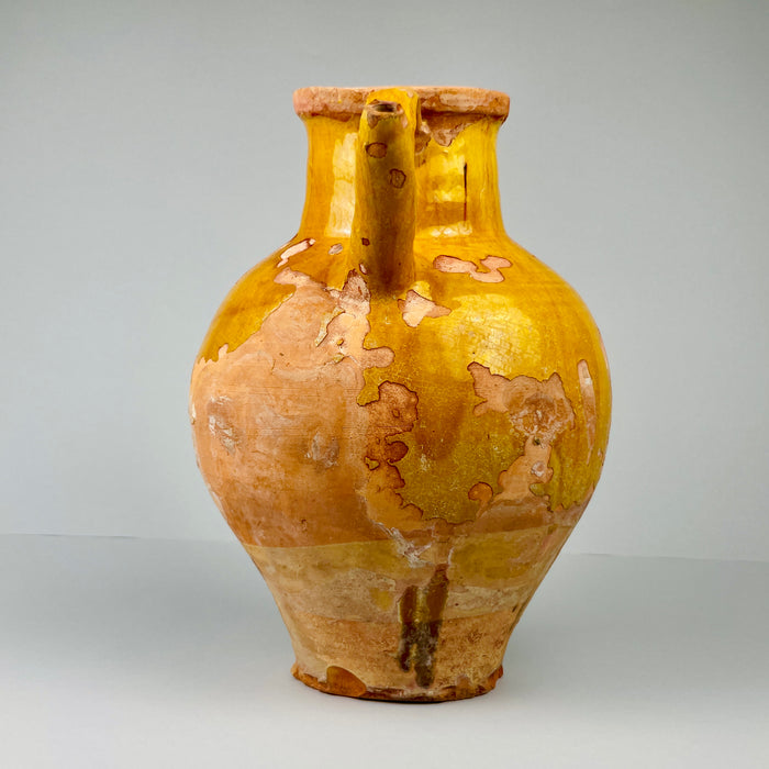 Yellow and brown ceramic vase on a white background. Top-down view of gargolette showing inner glaze and circular opening with rustic wear, suitable for use as a vase for dried branches or simply displayed as a statement antique pottery piece in rustic interiors.