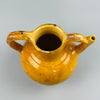 Warm light image of antique French jug with golden glaze reflecting softly, showing its authentic patina, chipped surface, and rounded form, ideal for farmhouse interiors, ceramic enthusiasts, or collectors of French pottery.