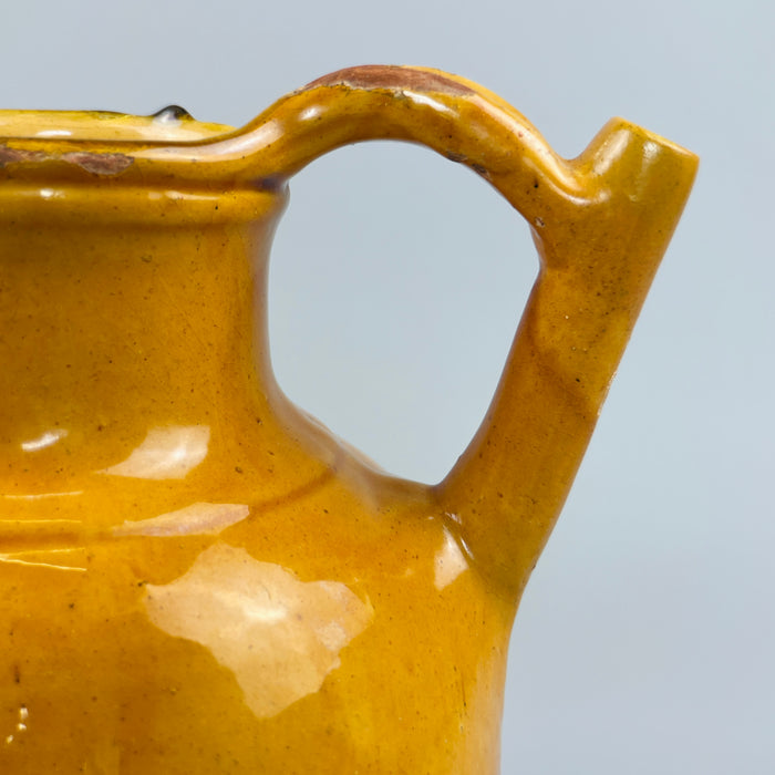 Surface detail shot showing glaze loss on the antique yellow pitcher, revealing red clay beneath, adding character and historical depth to this French provincial pottery piece, ideal for collectors of patinated ceramic vessels.