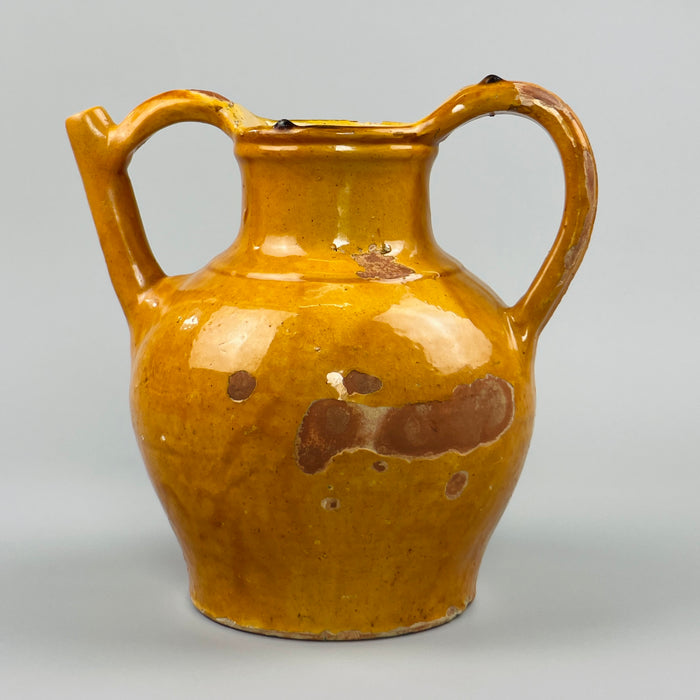 Side view of antique terracotta gargoulette with worn yellow glaze and bulbous form, showcasing traditional utilitarian pottery from Southwest France, perfect for use in rustic interiors, garden rooms, or farmhouse decor collections.
