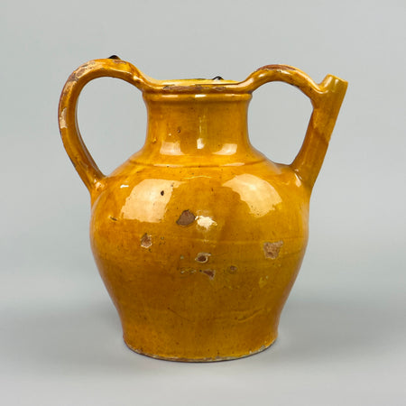 Antique French gargoulette water jug made of terracotta with vibrant yellow glaze, twin handles, and side spout, ideal as a rustic farmhouse accent or vintage Mediterranean pottery display in traditional or eclectic home settings.