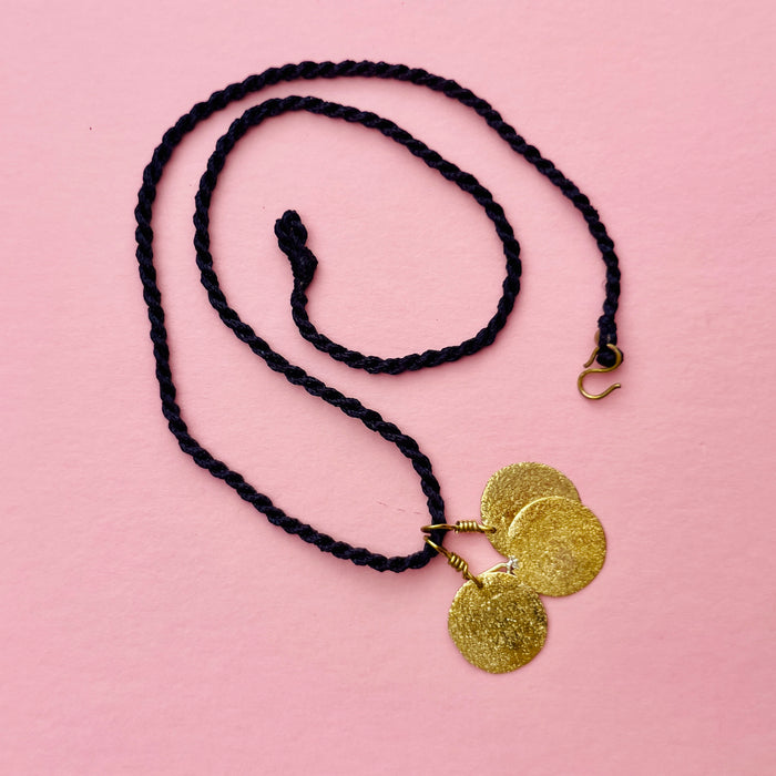 Final product close-up showing all three hammered discs shimmering in light. Keywords: gold-tone disc necklace, artisan hammered pendant, lightweight boho jewelry.