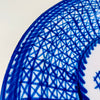 Spanish majolica plate from Manises with a signed painted mark, a white glazed ground, and bold cobalt ornament. Overlapping brush lines form a complex field of triangles and diamonds around the rim, while the center remains open around a stylized plant. The large antique charger brings graphic blue and white decor to a wall or display stand.