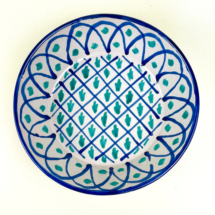 Large ceramic wall bowl inspired by Fajalauza pottery from Granada, Spain, with a pierced hanging hole on the reverse for vertical display. The hand painted blue and green design combines lattice geometry, vegetal motifs, and a deep bowl profile, making it suitable for Spanish ceramic decor and Mediterranean wall art.