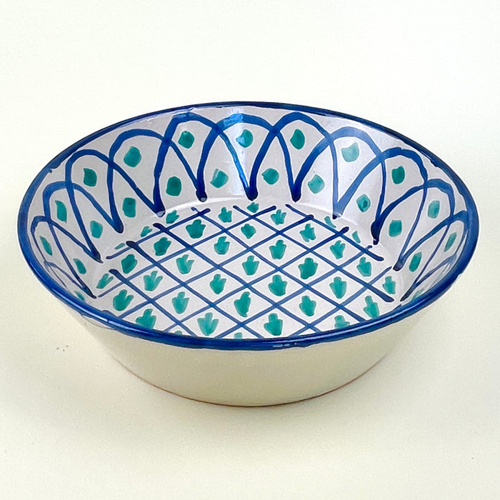 Large ceramic wall bowl inspired by Fajalauza pottery from Granada, Spain, with a pierced hanging hole on the reverse for vertical display. The hand painted blue and green design combines lattice geometry, vegetal motifs, and a deep bowl profile, making it suitable for Spanish ceramic decor and Mediterranean wall art.