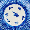Antique blue and white Manises plate with a signed mark and hand applied cobalt decoration. The geometric border varies in line weight, spacing, and pigment intensity, showing the individual brushwork behind the design. Scattered rim fritting, chips, and exposed earthenware preserve the aged character of this large Spanish majolica wall plate.
