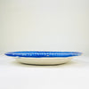 Large Spanish majolica plate attributed to Manises and dating to the early 20th century, with freely brushed cobalt decoration over an opaque white glaze. The shallow charger combines a densely patterned border with a quieter central field of stylized foliage and geometric marks, creating a strong statement piece for Mediterranean decor and eclectic decor.