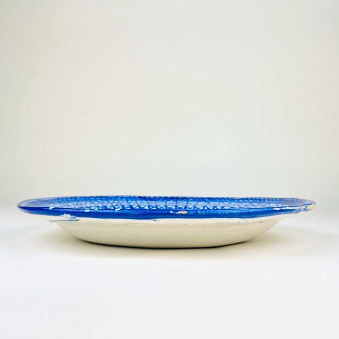 Large Spanish majolica plate attributed to Manises and dating to the early 20th century, with freely brushed cobalt decoration over an opaque white glaze. The shallow charger combines a densely patterned border with a quieter central field of stylized foliage and geometric marks, creating a strong statement piece for Mediterranean decor and eclectic decor.