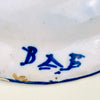 Blue and white Spanish charger from Manises, signed and hand painted on tin glazed earthenware during the early 20th century. The wide rim carries an energetic crosshatched pattern bordered by repeated cobalt strokes, while the center features one plant sprig and six surrounding symbols. The antique plate suits ceramic wall art and eclectic decor.