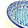 Spanish lebrillo bowl with pierced hanging hole, exposed terracotta clay edge, glossy white glaze, and bold green blue Fajalauza decoration. The deep rounded form suits wall display, fruit or bread presentation, farmhouse decor, Mediterranean decor, and collected Spanish ceramic interiors with handmade pottery character.