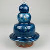 Triple-tier sculptural ceramic lid removed and displayed upright, revealing its gourd-shaped silhouette and rounded base, ideal as a design object for tabletop or cabinet display in curated interiors.