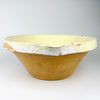 Early 20th century French terracotta tian bowl from Provence with a broad circular form, gently flared rim, small pouring notch, and pale yellow glaze over visible throwing rings. Glaze losses at the interior center and scattered chips around the rim reveal the natural clay body, creating authentic antique pottery character for rustic home decor.